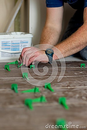 Close up hands of repairman laying tiles with tile leveling system on the floor in a new house Stock Photo