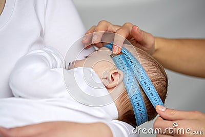 Close up of hands with tape measuring baby head Stock Photo