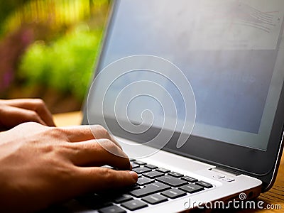 Close up of the hands of a tele worker typing on a laptop keyboard with a blurred background Stock Photo