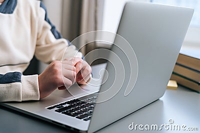 close-up hands unrecognizable child boy typing text using keyboard laptop sitting at desk with near window. Editorial Stock Photo