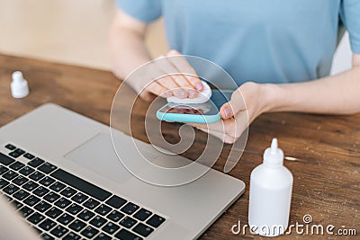 Close-up of hands of unrecognizable woman cleaning mobile phone with antibacterial sanitize Editorial Stock Photo