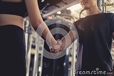 Close up handshake of sporty young asian woman with man greeting partner exercise workout at fitness gym Stock Photo