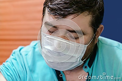 Close-up of a handsome man in a gauze mask with his eyes closed. Corona Covid-19. Caucasian patient, exhausted man in a medical ma Stock Photo