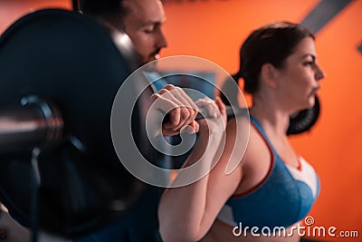 Close up of handsome trainer helping woman with lifting barbell Stock Photo