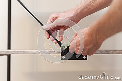 Close up of handyman adds the bookcase construction by screwing the bolts with a hexagonal wrench Stock Photo