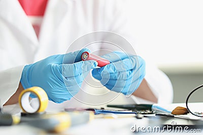 Handyman in gloves repair something electronical holding red battery detail Stock Photo