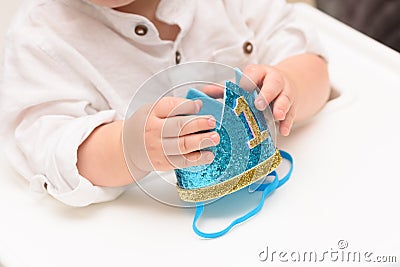 Close up on happy birthday baby boy hand with blue crown with digit one. Stock Photo