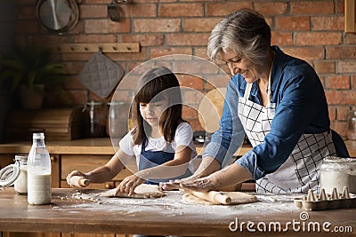 Close up happy grandmother with little granddaughter rolling out dough Stock Photo