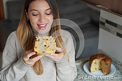 Close-up of happy young woman eating a slice of Panettone traditional Christamas cake with raisins and candied fruits indoor Stock Photo