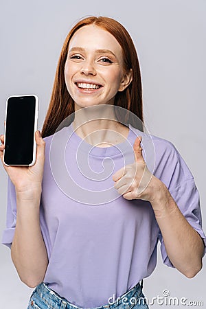 Close-up of happy young woman showing cell phone with black empty mobile screen and thumb-up gesture Stock Photo