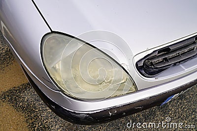 Close up hazy yellowed dirty car unpolished cloudy foggy front plastic automobile headlight worn Stock Photo
