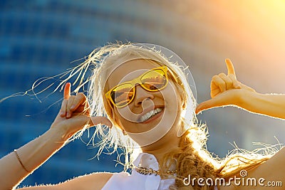 Close up head shot portrait of young woman wearing sunglasses. Happy girl standing under sunbeams and rejoicing summer. Blurred Stock Photo