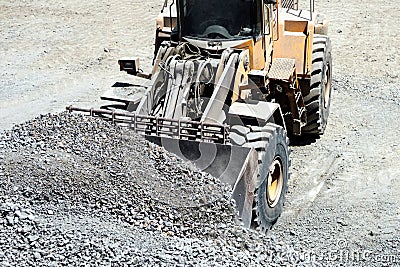 Close up of heavy duty large wheel loader loading gravel at work site Stock Photo