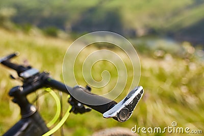 Close-up of helm of the mountain bicycle in the green grass against beautiful landscape. Stock Photo