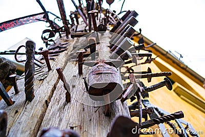 Close up of a high wooden pole Journeymen Pillar with iron/steel nails bolted in it, as a symbol of craftsmanship. Stock Photo