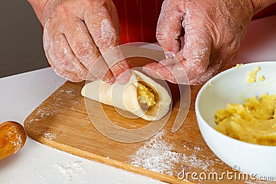 Close-up, homemade cooking. Senior woman in red kitchen apron sc Stock Photo