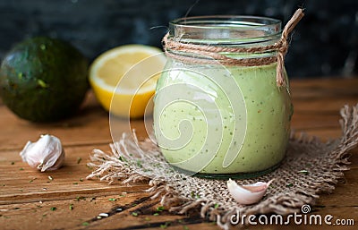 Close-up of homemade creamy avocado dressing in a jar on wooden background Stock Photo