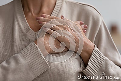 Close up hopeful grateful mature woman keeping hands on chest Stock Photo
