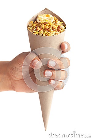 Close-Up of Hot spicy Nav Ratan snacksin brown paper cone holding in hand isolated over white Stock Photo