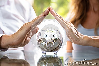 Human Hand Protecting Piggy Bank Stock Photo