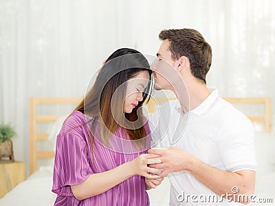 Close up husband man kiss forehead woman belly sitting on the bedroom Stock Photo
