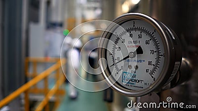 Close up of hydraulic pressure gauge at the factory. Scene. Blurred background with workers in a narrow corridor of a Editorial Stock Photo