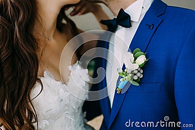 Close-up image of a Boutonniere on the groom`s jacket. Blurred bride and groom are kissing. Artwork Stock Photo