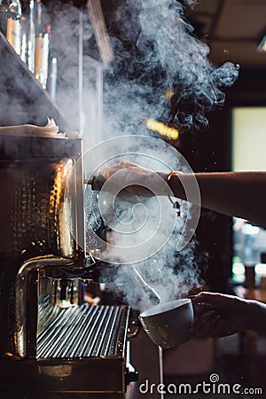 Close-up image of female barista using coffee-making machine to steam milk in cafe Stock Photo
