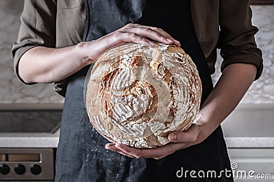 Close-up image of female hands holding big loaf of white bread. Stock Photo