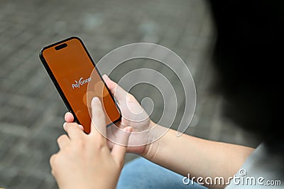 Close-up image of a female using Payoneer application while relaxing outdoors Editorial Stock Photo