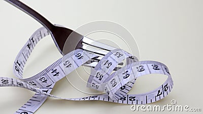 Close-up image of a fork rolling a tape measure. Stock Photo