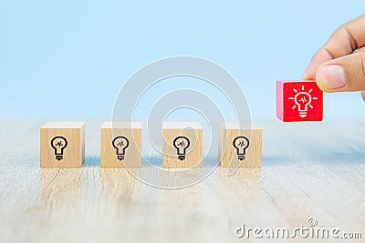 Close-up image of hand-picked cube shaped wooden toy blocks with light bulb symbol stacked ideas for creativity Stock Photo