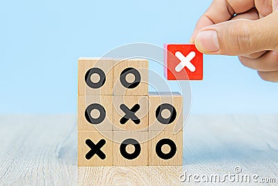 Close-up image of hand-picked cube shaped wooden toy blocks with X symbol stacked for business management and strategy Stock Photo