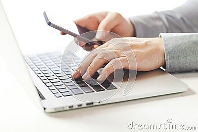 Close up image of multitasking business man using a laptop and mobile phone Stock Photo