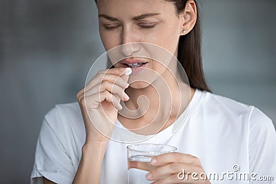 Woman holds glass of water takes painkiller for headache reducing Stock Photo