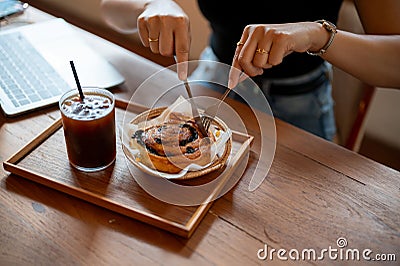 Close-up image of a woman eating a yummy croissant roll, and iced coffee in a cafe Stock Photo