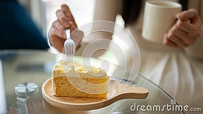 Close-up image of a woman enjoys eating a yummy cake while relaxing in a coffee shop Stock Photo