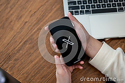 Close-up image of a woman using X Twitter platform on her Iphone14 at her desk Editorial Stock Photo