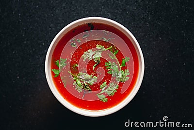 Close-up of Indian Homemade fresh tomato soup garnished with fresh coriander leaves and dry mint or basil leaves, Stock Photo