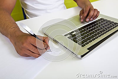 Close up of Indian mans hands writing on paper next to laptop Editorial Stock Photo