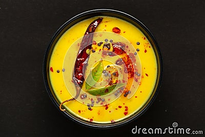 Close-up of Indian traditional kadhi or kadi pakora yogurt and gram flour and turmeric served hot in a black bowl. Stock Photo