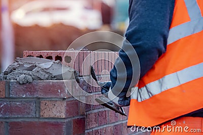 Close up of industrial bricklayer laying bricks on cement mix on construction site Stock Photo