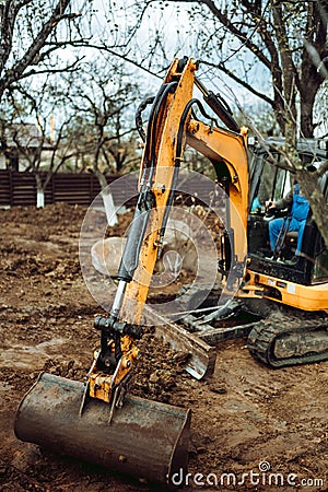 Close up of industrial mini excavator scoop moving earth and doing landscaping works Stock Photo