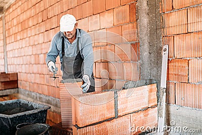 Close up of industrial worker, bricklayer installing bricks on interior building at construction site Stock Photo