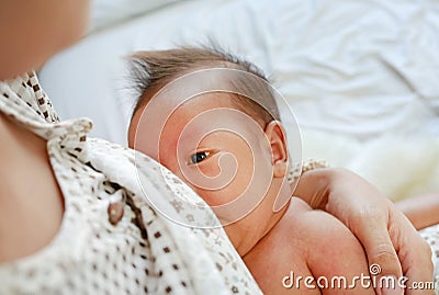 Close-up infant baby feeding from mother breastfeeding her newborn child on the bed Stock Photo