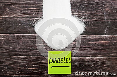 Inscription diabetes on a yellow sticker on a sugar background. View from above. Wood background. Stock Photo