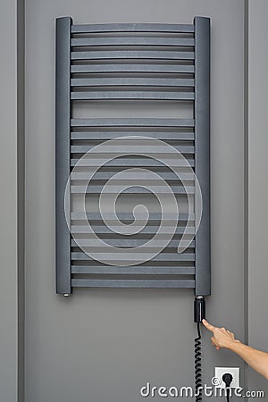 Close-up interior elements of bathroom, towel radiator. Gray electric thermostatic heated towel rail. women`s hand make temperatu Stock Photo