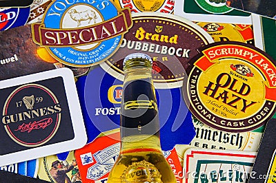 Close up of international beer coaster boards from all over the world with yellow bottle Editorial Stock Photo