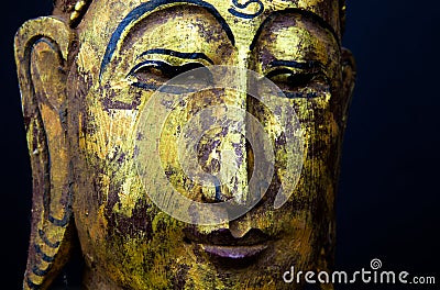 Close up of isolated ancient gold paint wood Buddha head face of thai statue in buddhist temple Stock Photo
