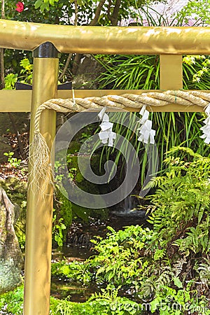 Close up on a Japanese golden torii gate and a sacred shimenawa straw rope in Japan. Stock Photo